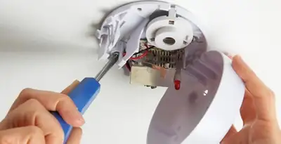 Certified technician wiring smoke detector during installation in Sacramento, CA